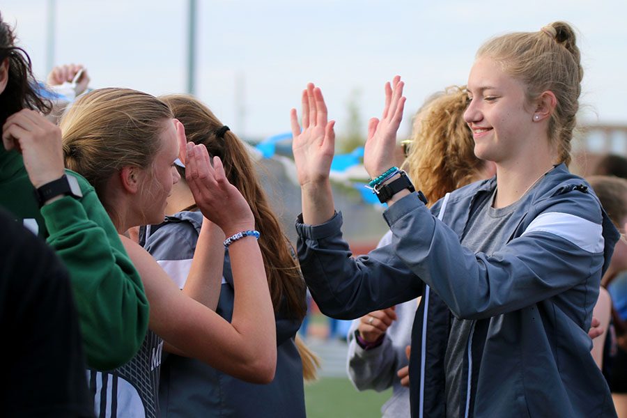 Holding her hands up for a high five on Friday, April 26, sophomore Josie Taylor congratulates freshman Katie Schwartzkopf on her run during the Trailblazer Invite. 