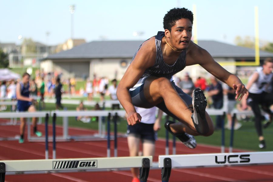 Finishing his race junior Zack Mills jumps over a hurtle.