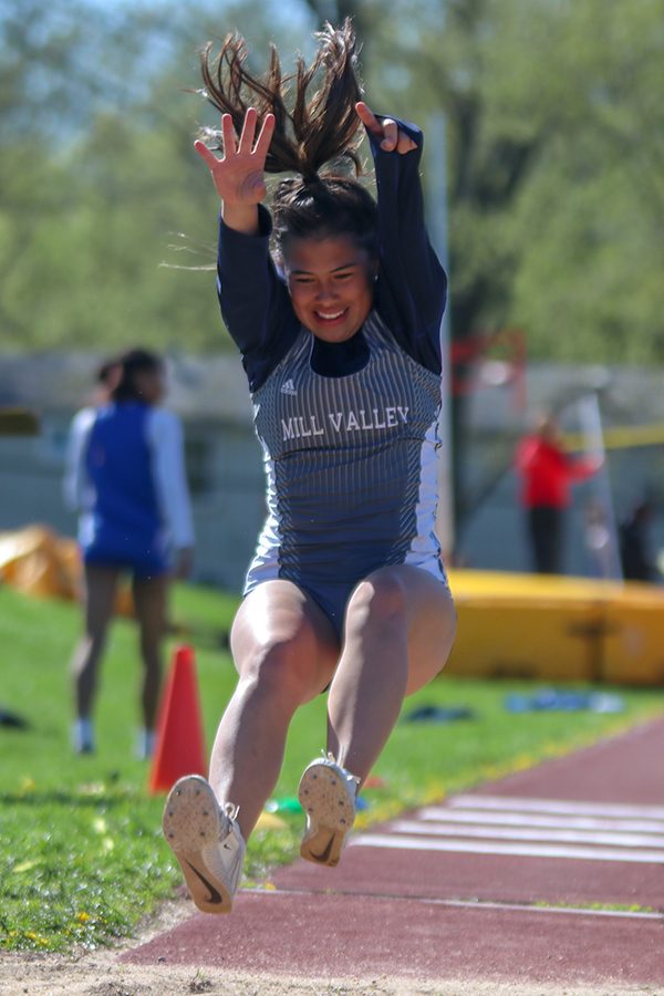 After running down the runway, senior Mya Johnston throws her arms and legs in the air to gain more distance in the triple jump. 