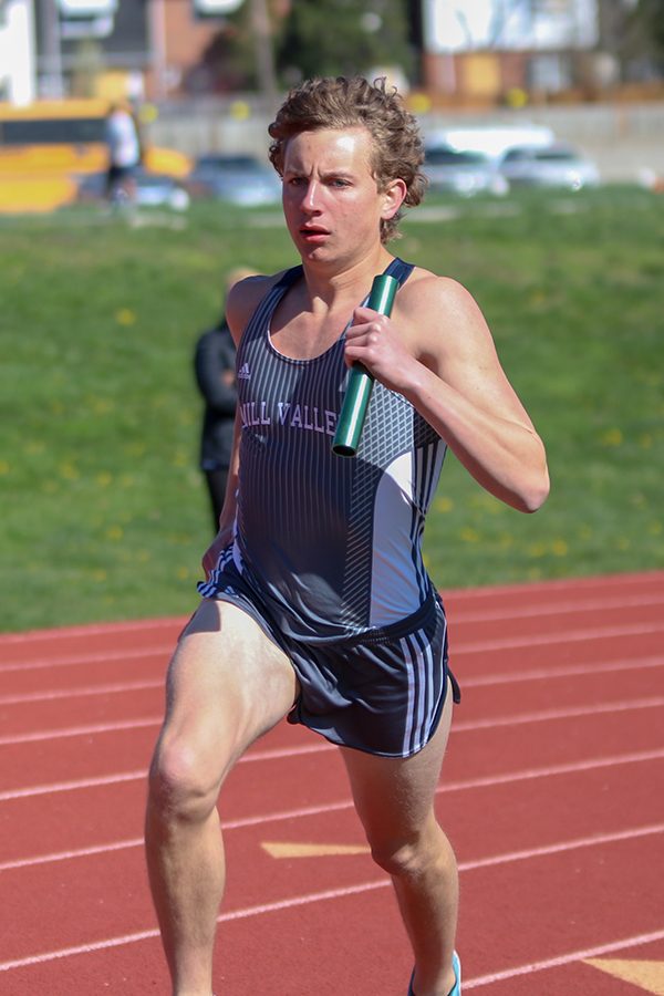  Carrying the baton in one hand, senior Jakob Twigg starts running his leg of the 4-by-800-meter relay. 