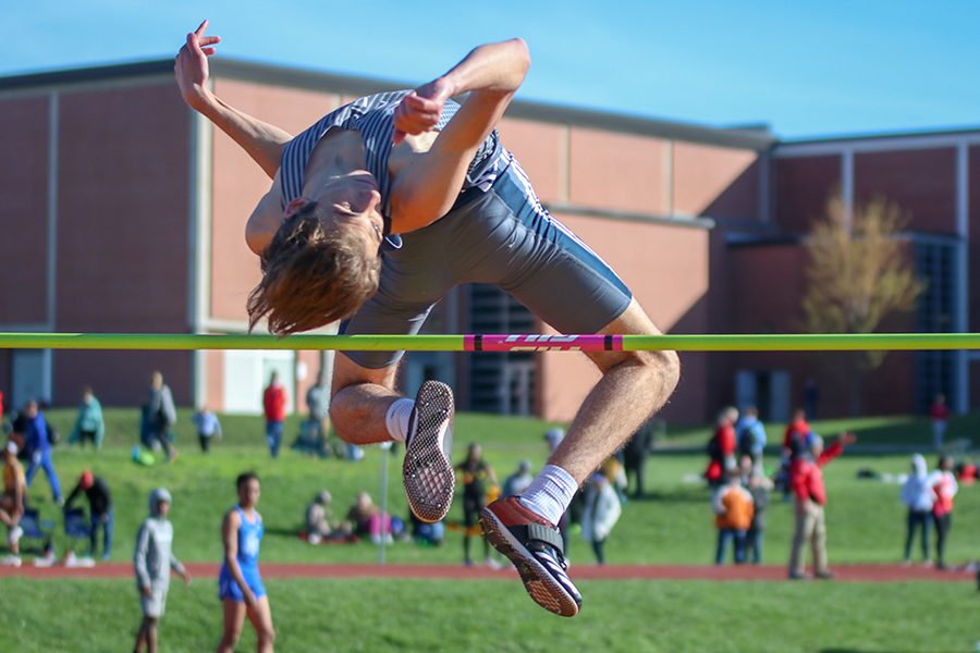 Looking down towards the mat, junior Anthony Runk jumps over the bar in the high jump event.