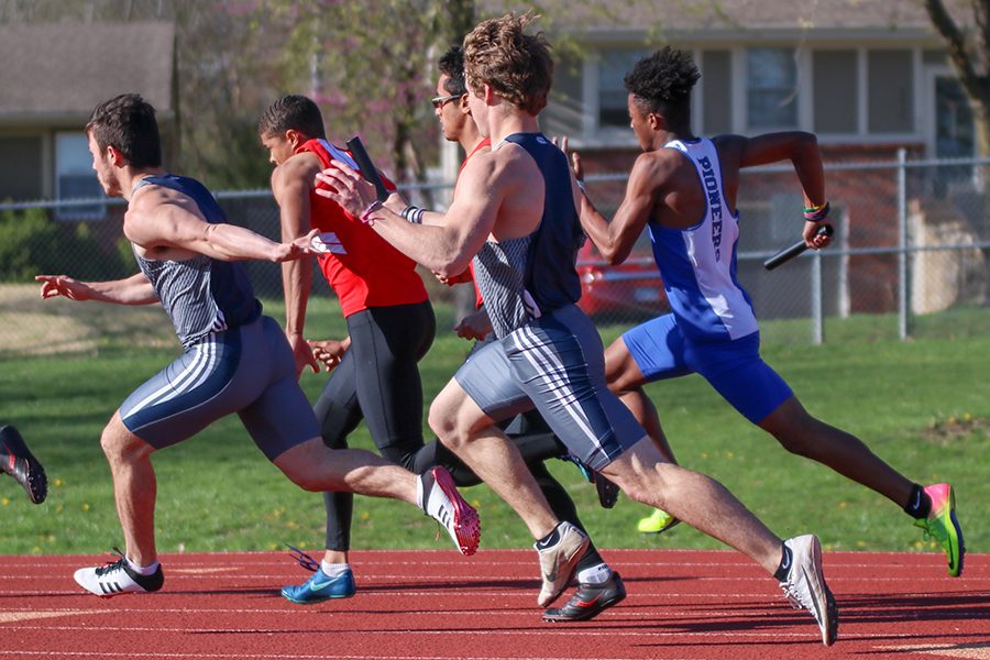 Completing the first leg of the 4-by-100-meter relay, senior Steven Colling hands the baton off to senior Henry Lopez. 