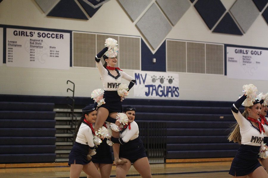 Pom Poms in hand, juniors Ali Greenhalgh and Samantha Pennington lift sophomore Lauren Acree. 