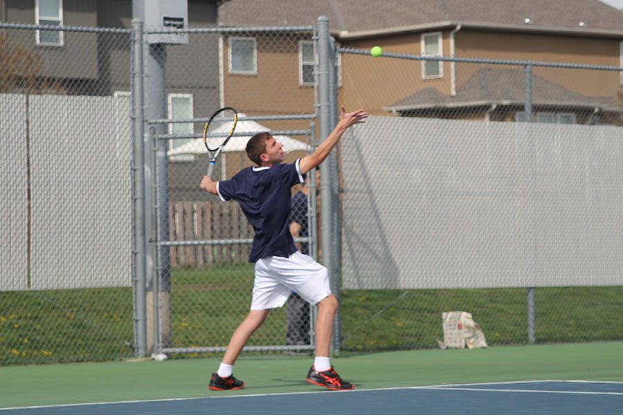 Throwing up the ball, sophomore John Scarpa serves the ball.
