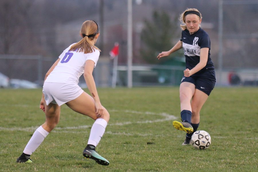 As a defender applies pressure, sophomore Anna Ricker kicks the ball to a teammate.