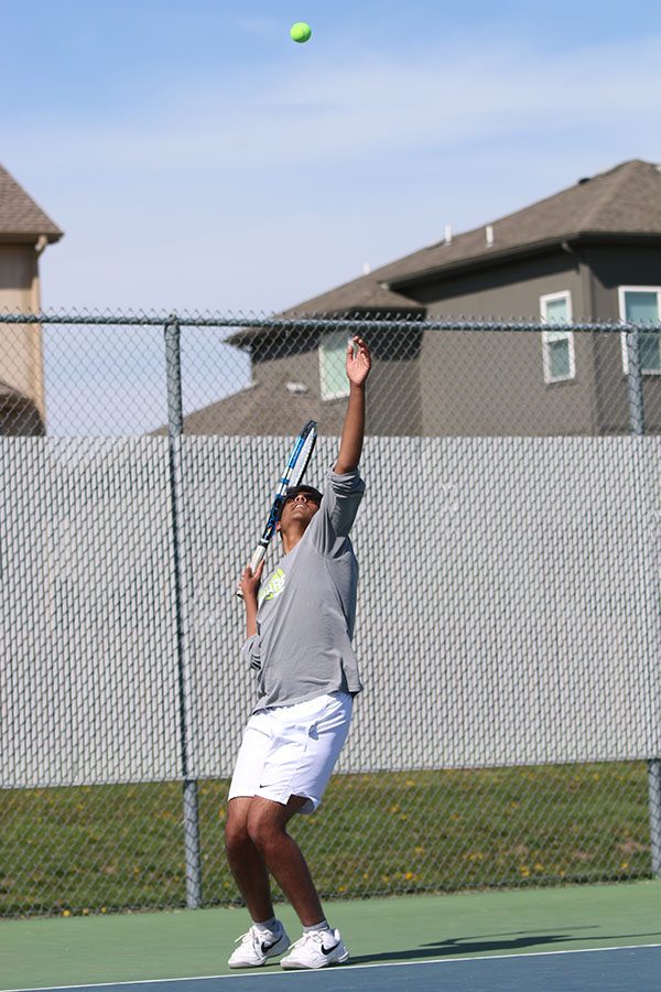 Beginning a new game, junior Srikar Turaga tosses up the ball for his serve.