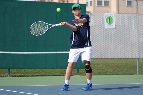 Setting his feet near the service line, senior Andrew Lewis hits a forehand return.