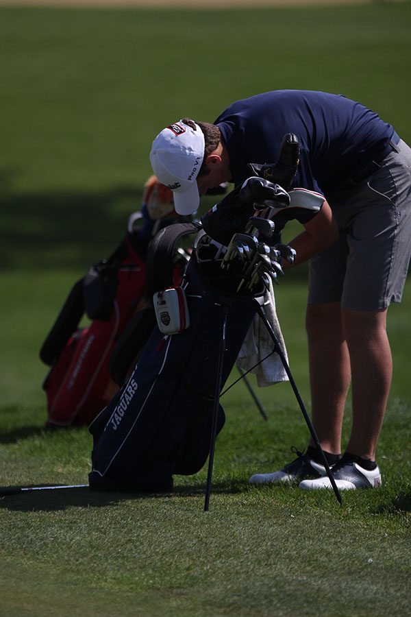 Looking through his bag, sophomore Nicklaus Mason pulls out his putter.