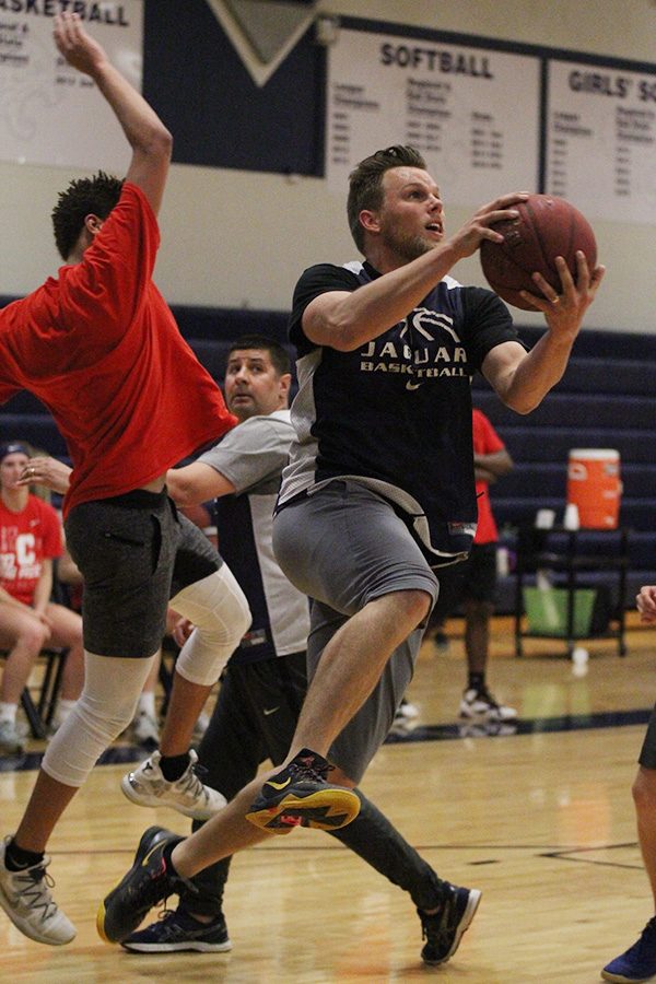 Jumping up, paraprofessional Zach McFall moves to shoot a basket during the Student vs. Faculty game on Tuesday, April 30.