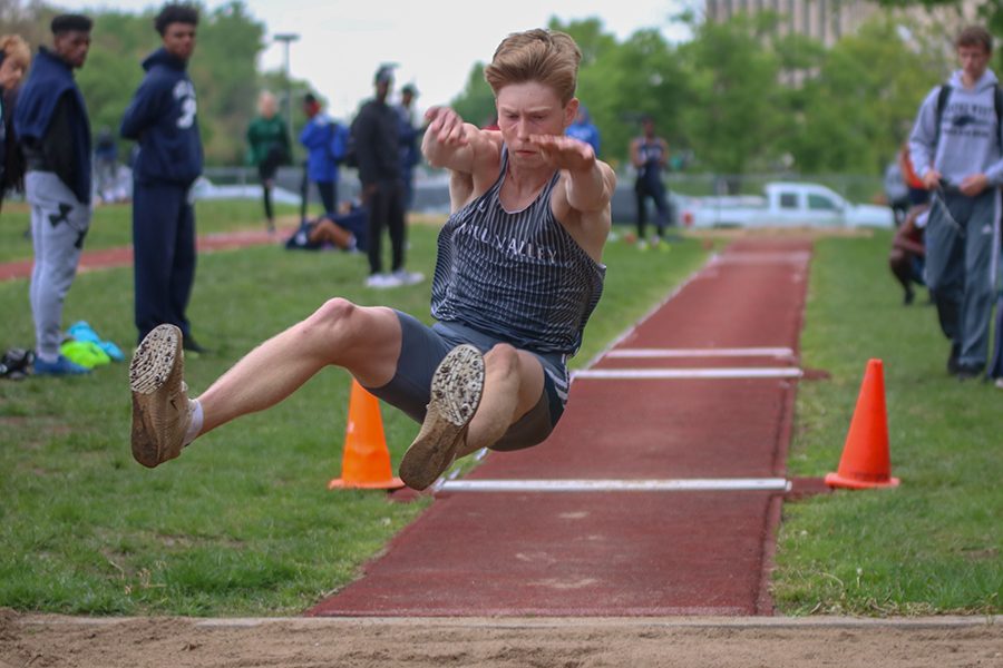 Stretching his limbs out to gain the more distance, senior Harry Arenholtz competes in the long jump.