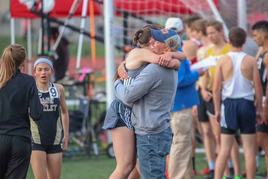 After finishing the 1600 meter run, senior Delaney Kemp and head track coach Chris McAfee hug. 