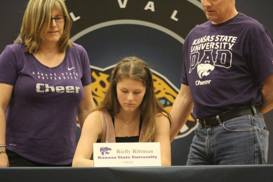 After signing to cheer at Kansas State University, Rielly Rittman sits next to her parents.
