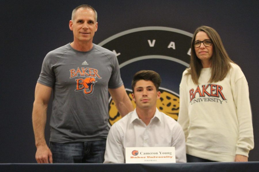 After signing to play football at Baker University, Cameron Young smiles with his parents.