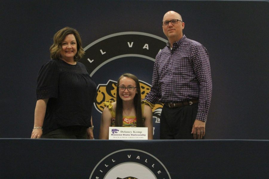 After signing to run cross country and track and field 
 at Kansas State University, Delaney Kemp smiles with her parents.
