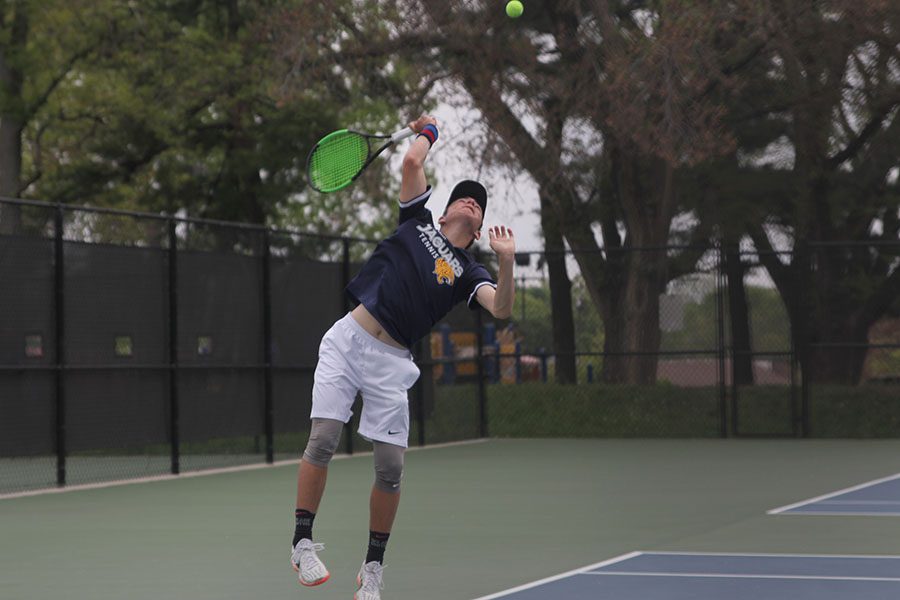 Serving the ball, freshman Gage Foltz jumps.  
