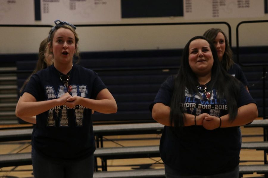 Clasping their hands in front of them, seniors Claire Segura and Ashlyn Windmiller sing to “Mr. Blue Sky” By Roger Emerson.