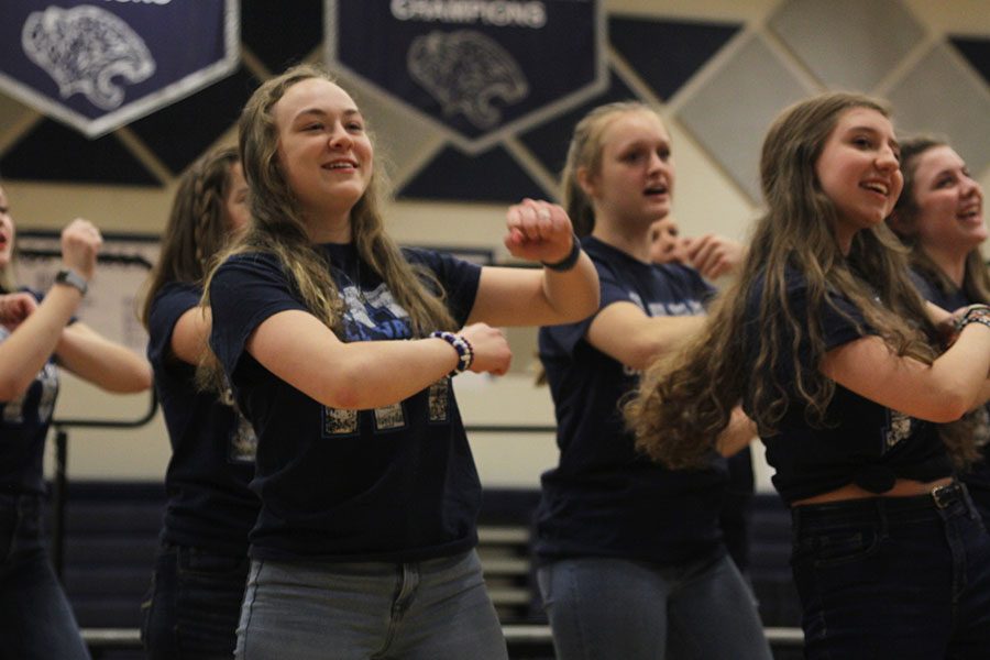 Smiling toward the crowd, junior Trinity Ouellette dances alongside members of the Grace Notes choir.