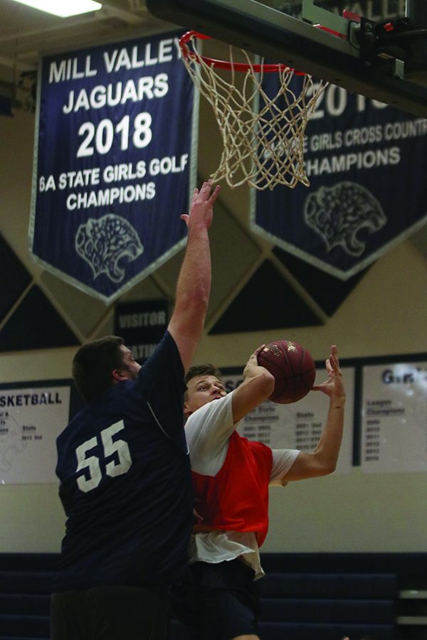 As senior Dustyn Sweet goes up for a layup, business teacher Kurt Bangle blocks the shot with grace