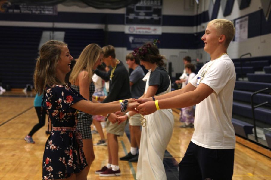 Two freshmen smile and laugh while dancing during an icebreaker game.

