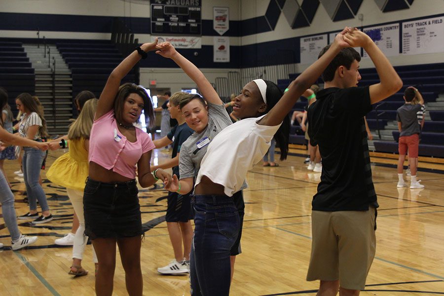 Two pairs of freshmen practice square dancing moves during an icebreaker activity. 
