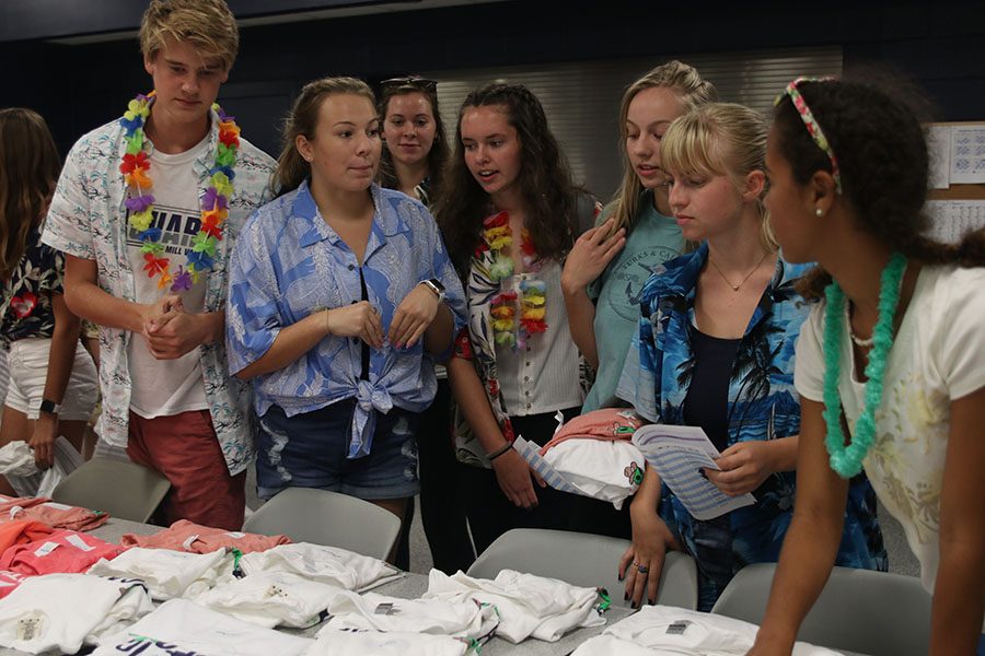 StuCo members sophomores Bret Weber, Allison Seck and freshman Gabby Delpleash help fellow students with their shirts.