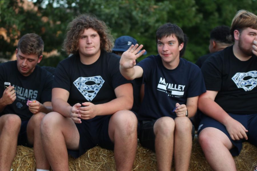 Sitting on the football float, senior Nick Pettigrew waves to a crowd of kids.