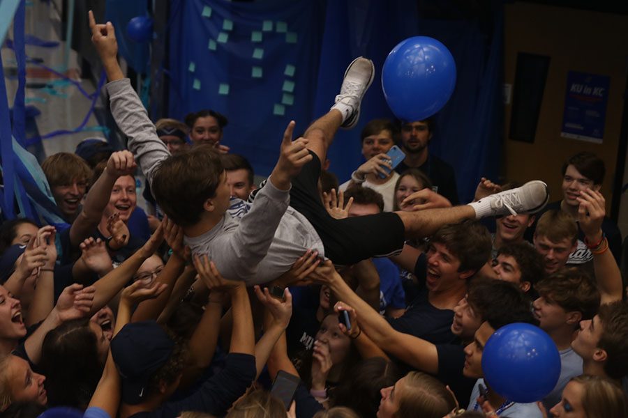 Being held up by the crowd, senior Gavin Koppa cheers. 