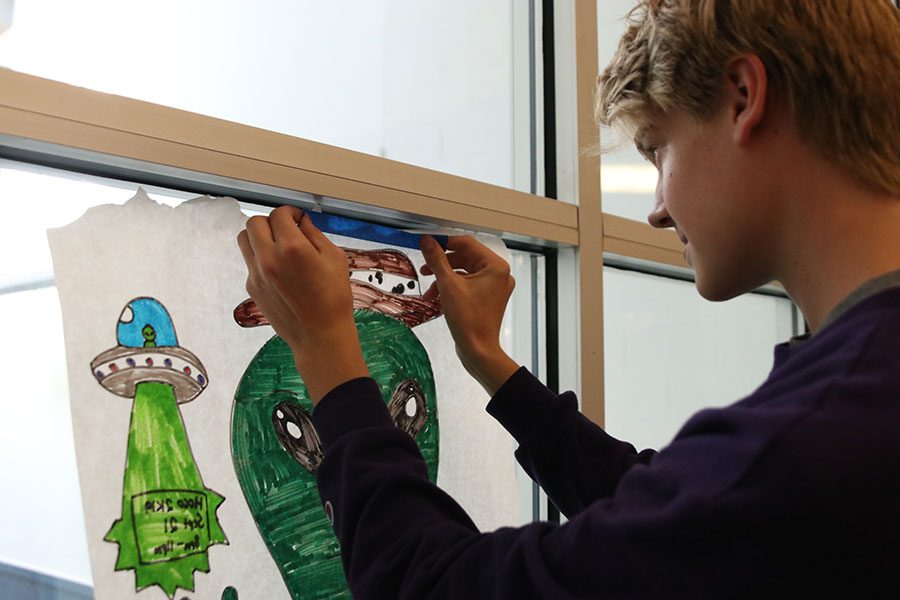 Sophomore Bret Weber hangs up homecoming posters for StuCo. 