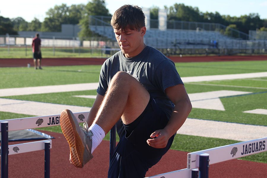 Lifting his leg over the hurdle, senior Carson Caldwell works out on the track due to the construction making the old weight room inaccessible. 
