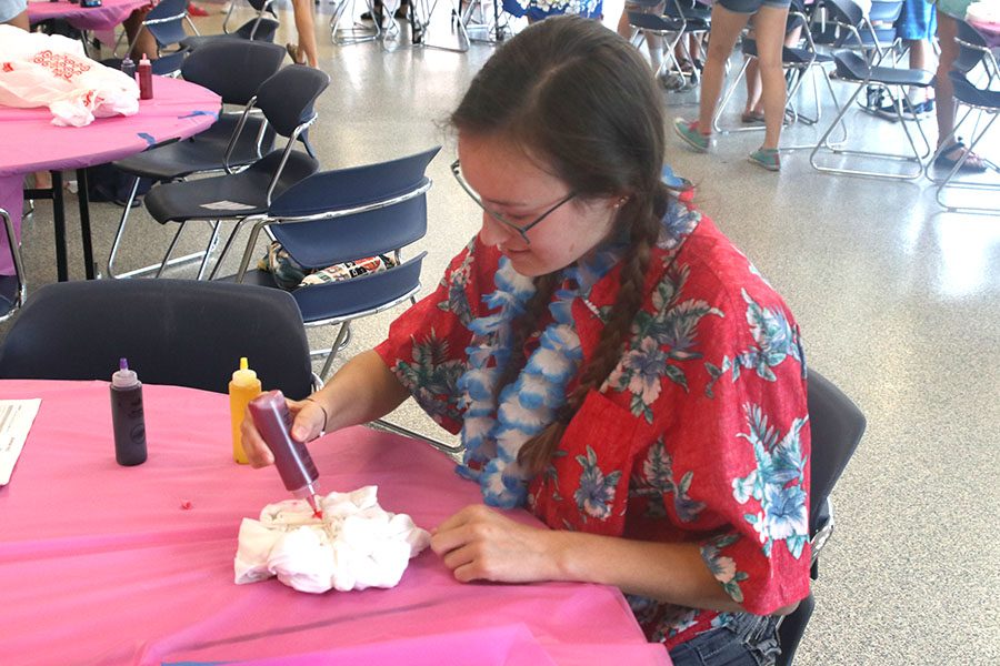 Squeezing the dye onto her T-shirt, senior Ella Armstrong colors her shirt red.
