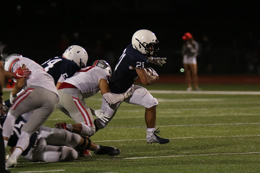 Getting pulled down by the opposing team, senior Tyler Green runs with the ball. 