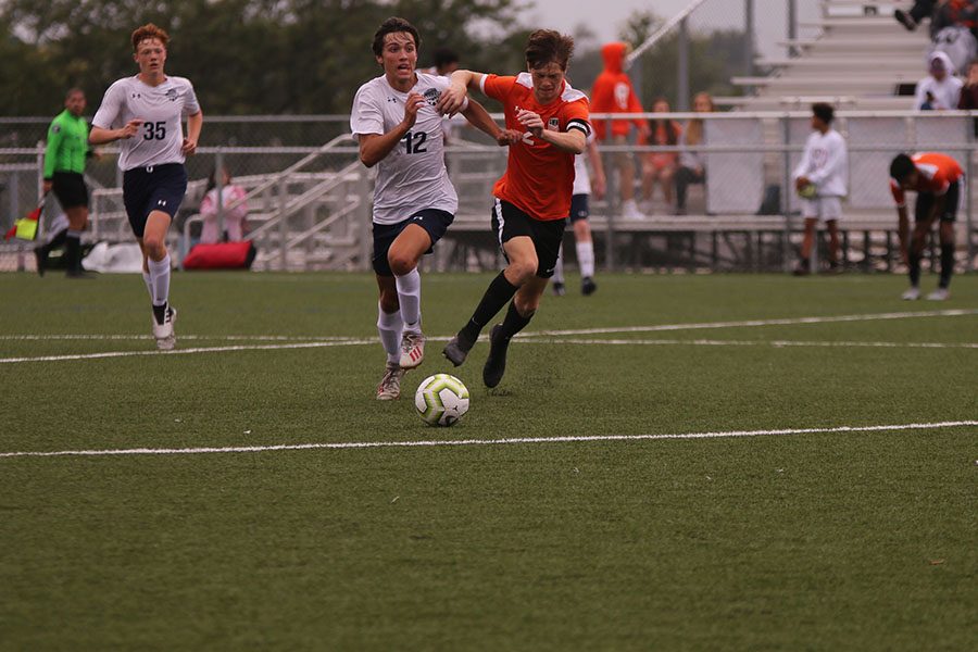 Battling his opponent, senior Anthony Pentola looks across the field and pushes forward.