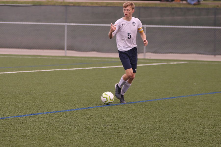 Motioning to his teammate to come receive the pass, senior Ian Carroll slowly dribbles up the side of the field. 