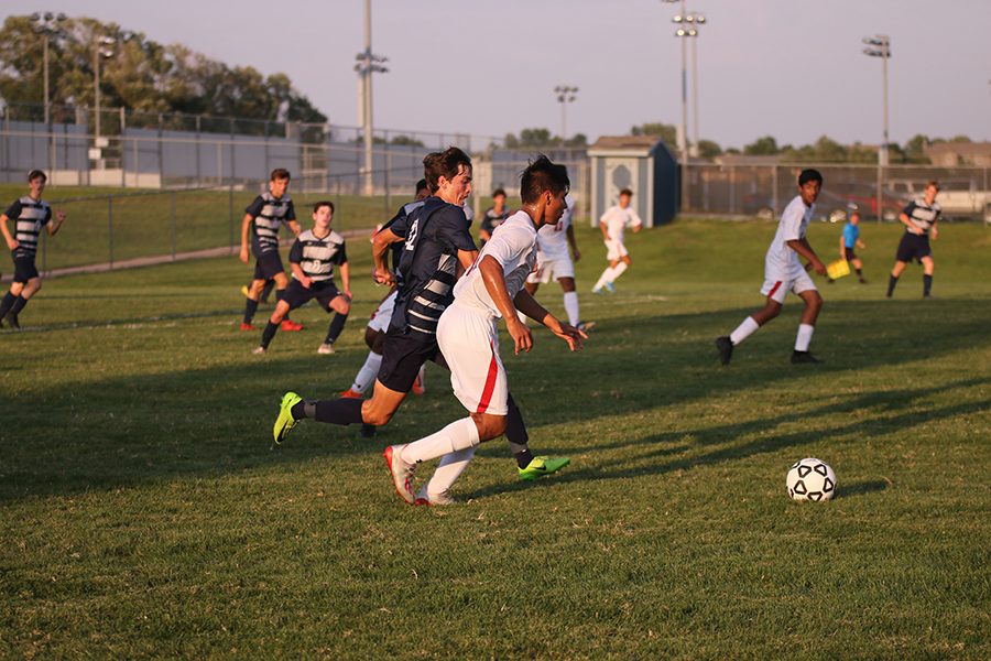 Trying to block his opponent, senior Anthony Pentola kicks the ball in front of him and his opponent and pushes the ball up the field.  I am looking forward to [the] playoffs and seeing how far we can get as a team, Pentola said. Pentola and the boys varsity soccer team battled Olathe North on Thursday, September 5th. 