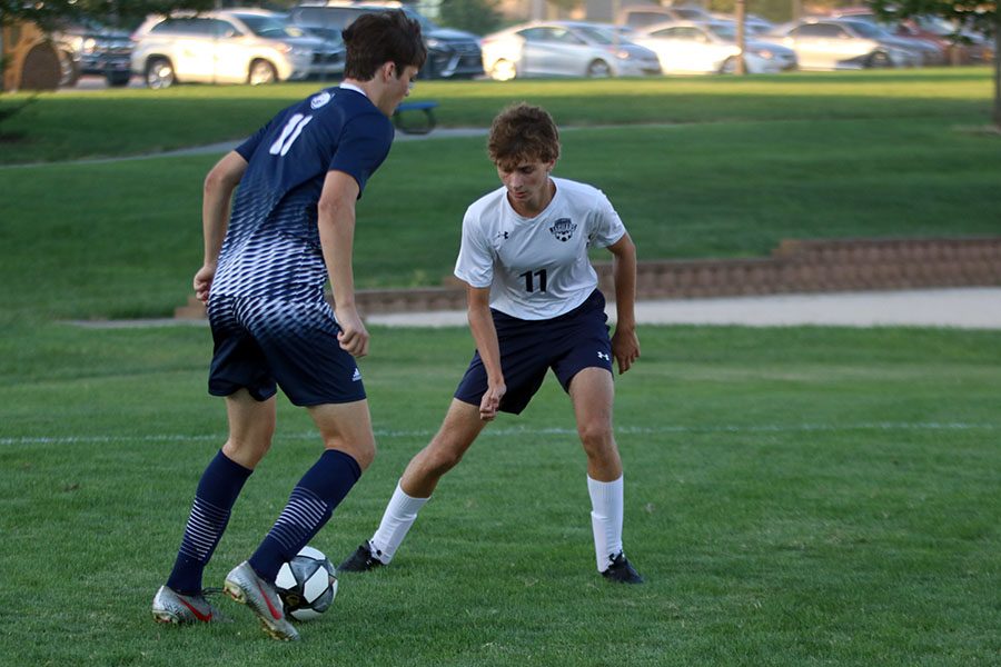 Blocking his opponent, junior Max Eber attempts to retrieve the ball.