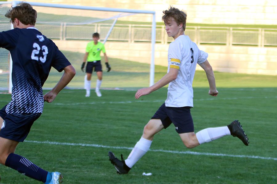 Watching the ball carefully, junior Greyden Gustafson catches up to an opponent.