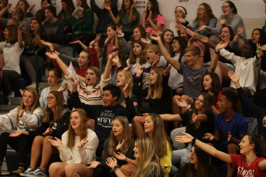 With hands over their heads, students yell a cheer with smiles on their faces