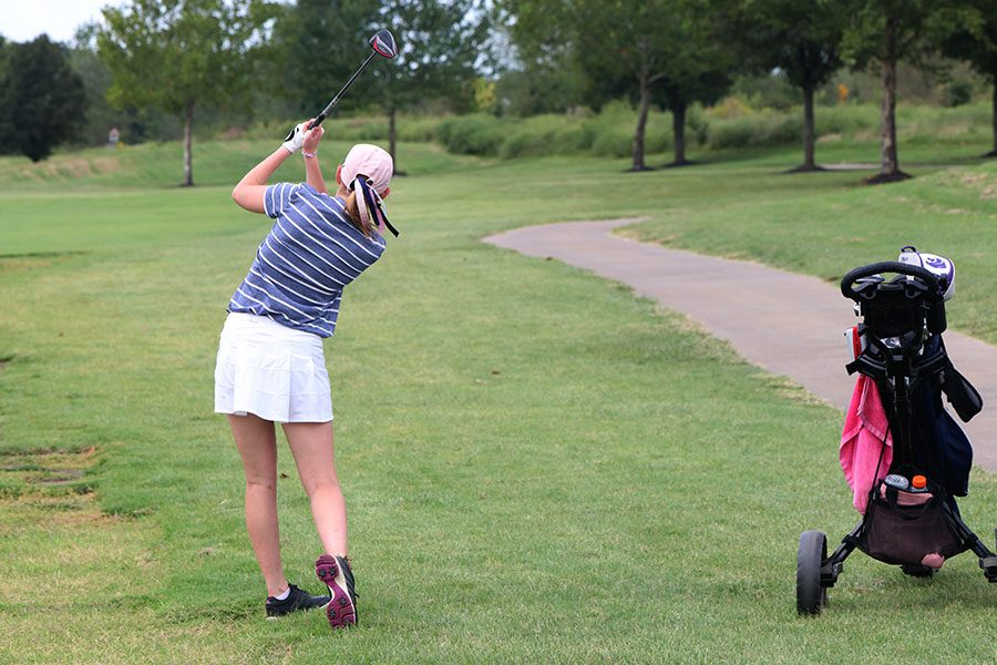 Following through with her driver, junior Ava Van Inwegen attempts to get her ball on the green.