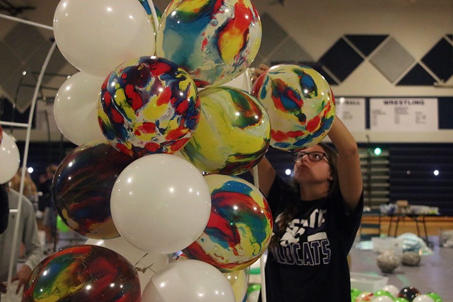 Junior Katherine Weigel ties balloons together to create a balloon arch. 