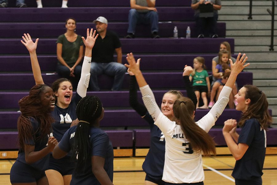 The volleyball team celebrates together after scoring a point.