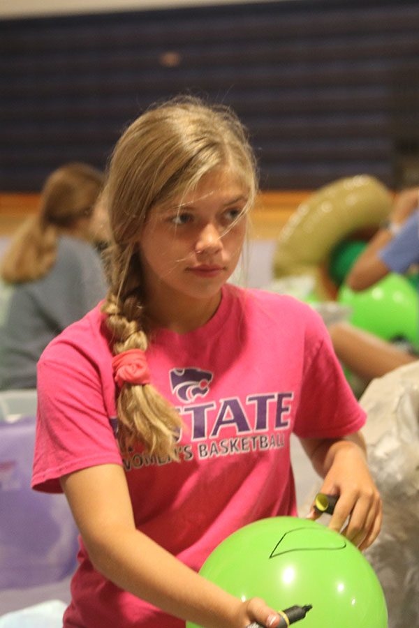 Freshman Brianna Coup helps decorate green balloons to look like aliens.