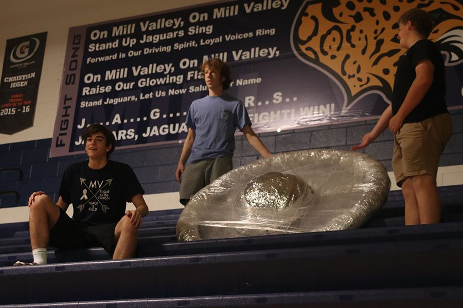 Junior Dutch Platt, senior Bennett Doyle, and sophomore Declan Taylor set up the UFO decoration on the bleachers.