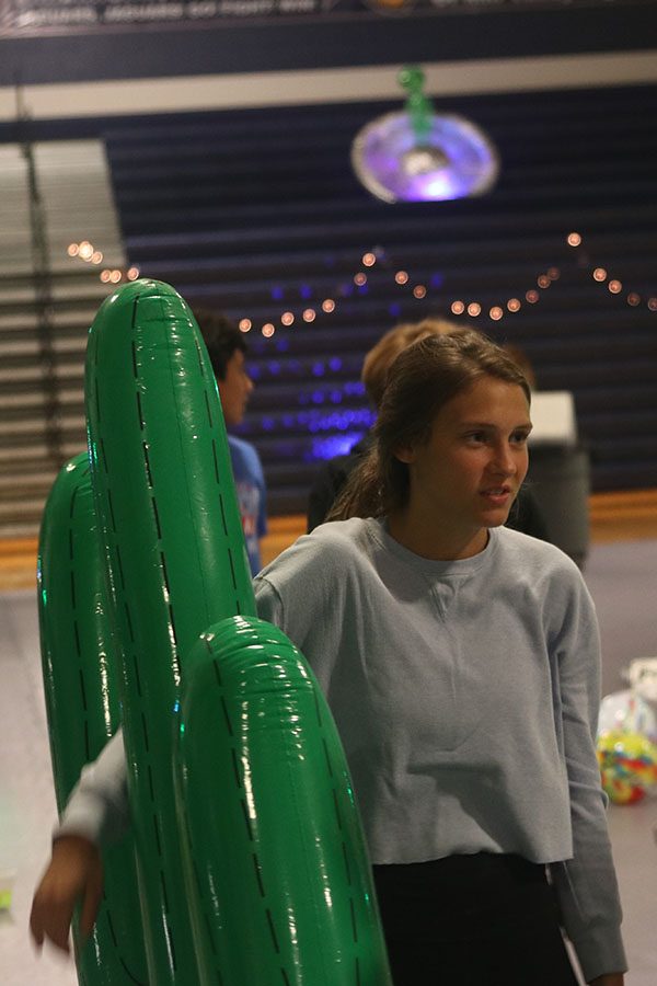 Senior Avery Altman holds an inflatable cactus as she discusses the dance with friends.