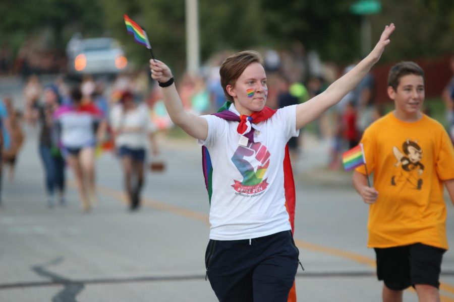 Ahead of the GSA float in the Homecoming parade, senior Jay Zuch waves a rainbow flag. 