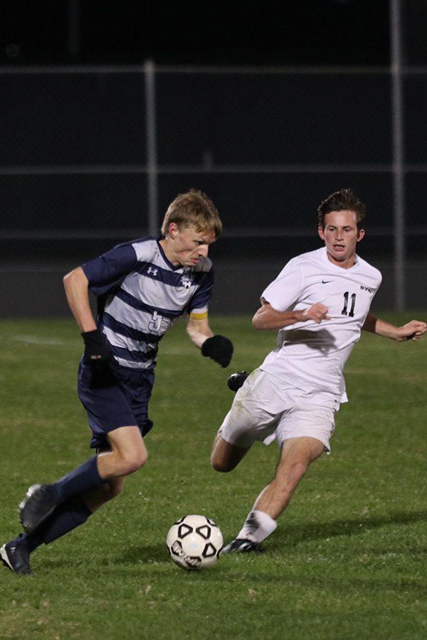 Running by his opponent, senior Ian Carroll dribbles up the field.