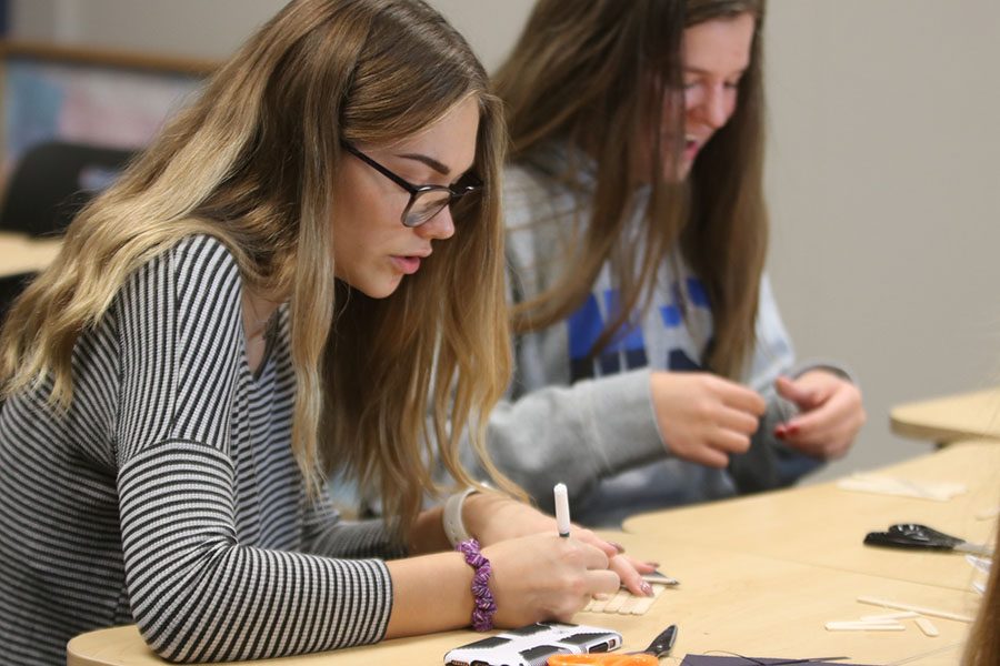 Junior Emma Hookstra talks to her friends while working on her popsicle art.