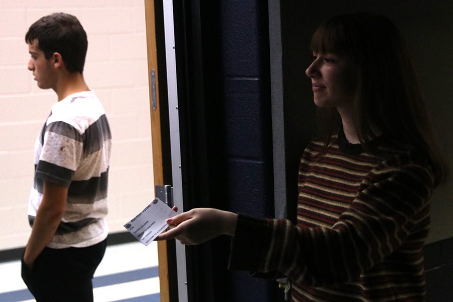 Smiling, sophomore Soledad Stevanov hands students voting ballots where they will vote for their favorite film.