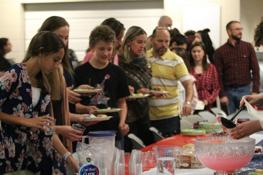 Lined up, students and their families get food at the reception.