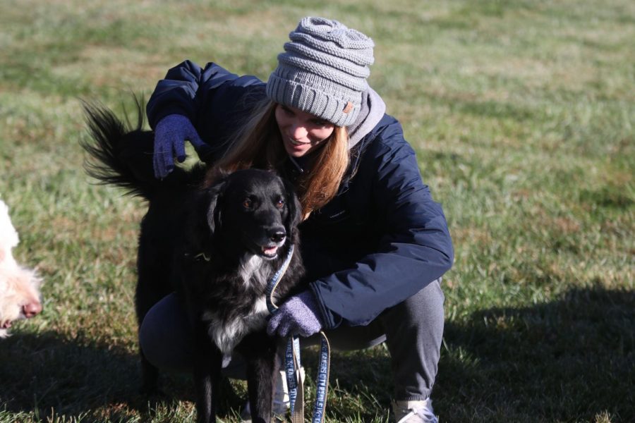 Crouching down, junior Ellie Boone pets her dog.