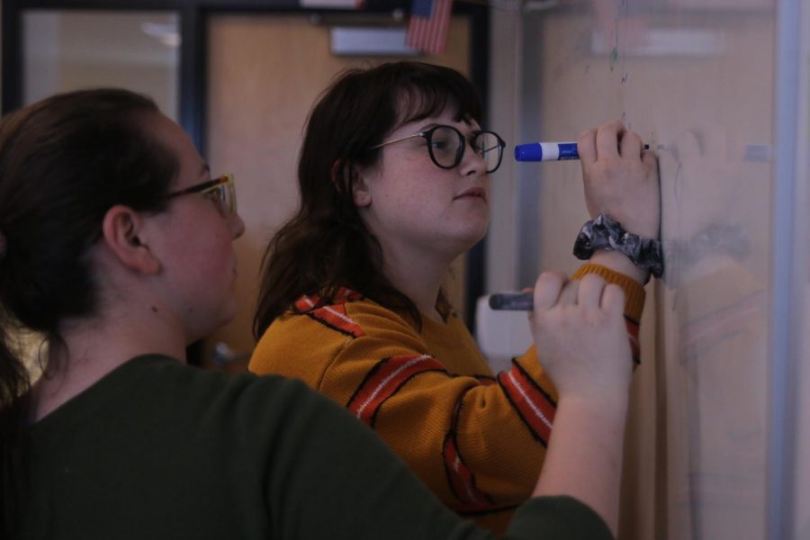 Writing on the whiteboard, junior Madelyn Augustine and senior Madelynn Hodes draw the agenda for the GSA meeting on Tuesday, Oct. 9. 
